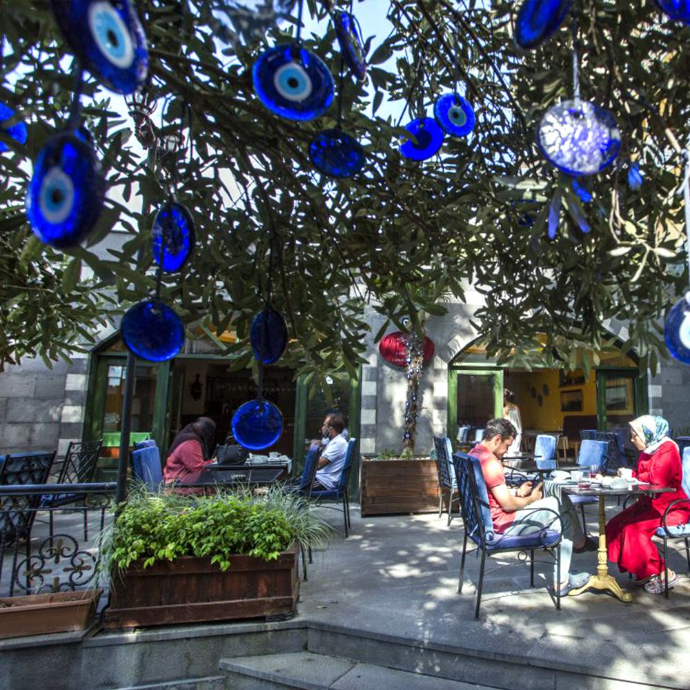 Blue nazar (evil-eye) charms strung through the tree over the tables